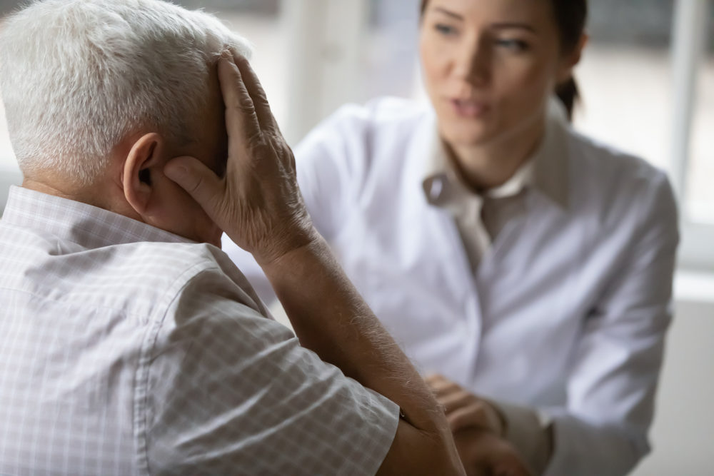 Professional female general practitioner treating unhealthy elderly mature retired man.